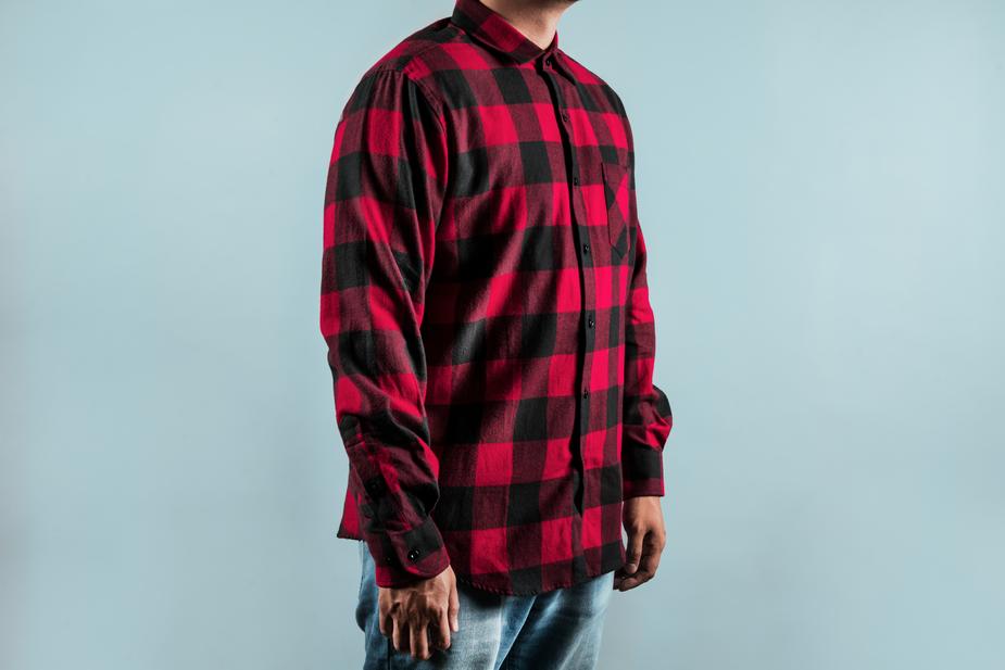 a man in a red and white striped shirt standing on a skateboard 